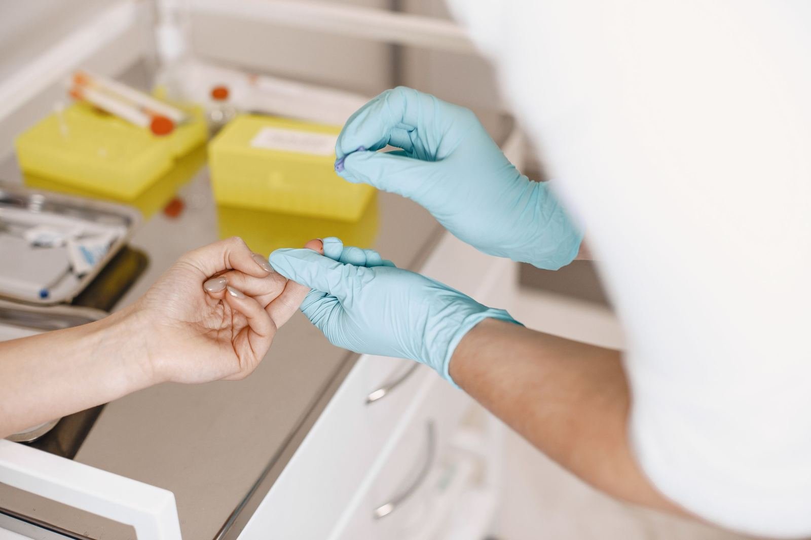 Profesional de la salud con guantes tomando una muestra de sangre del dedo de un paciente para una prueba rápida en consultorio
