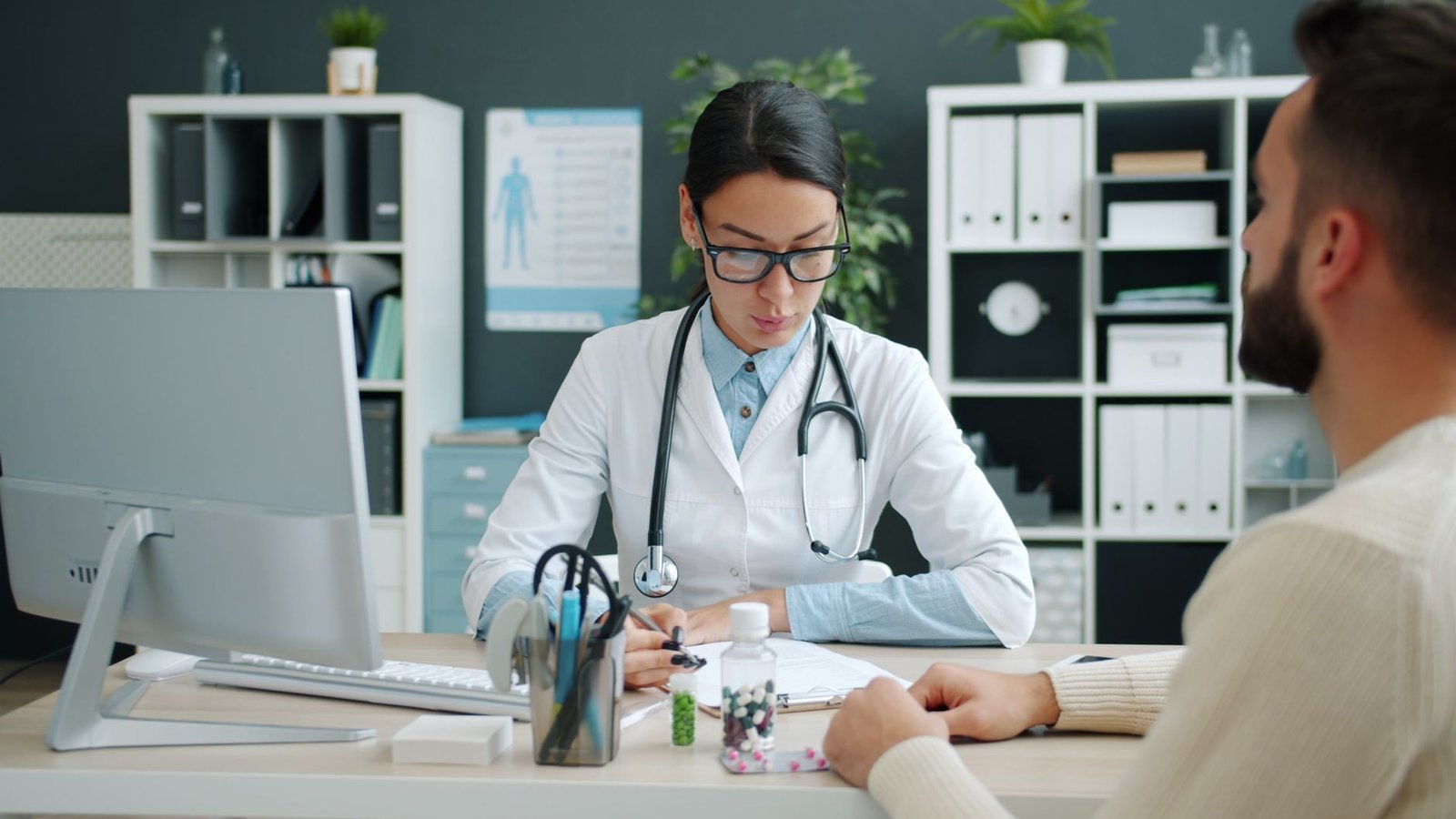 Una doctora revisa documentos y medicamentos junto a un paciente en un consultorio moderno