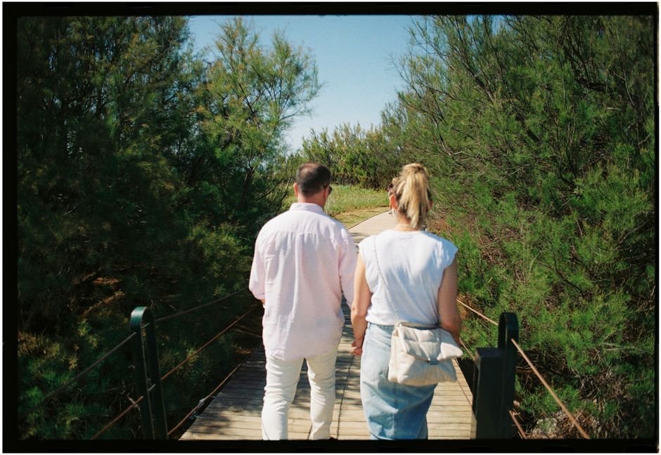 Pareja tomada de la mano vista de espaldas caminando al aire libre, ilustrando la conversación honesta sobre prevención y contagio de herpes genital.