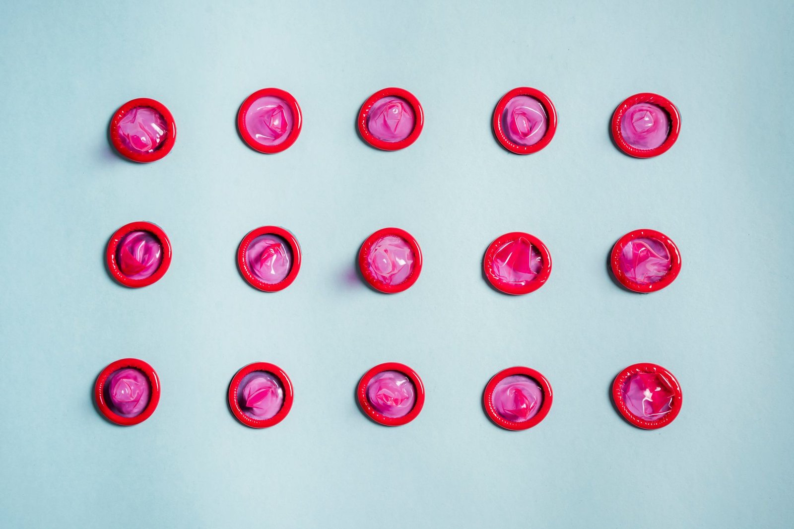 Condones organizados en filas ordenadas sobre un fondo de color, sin texto ni marcas visibles