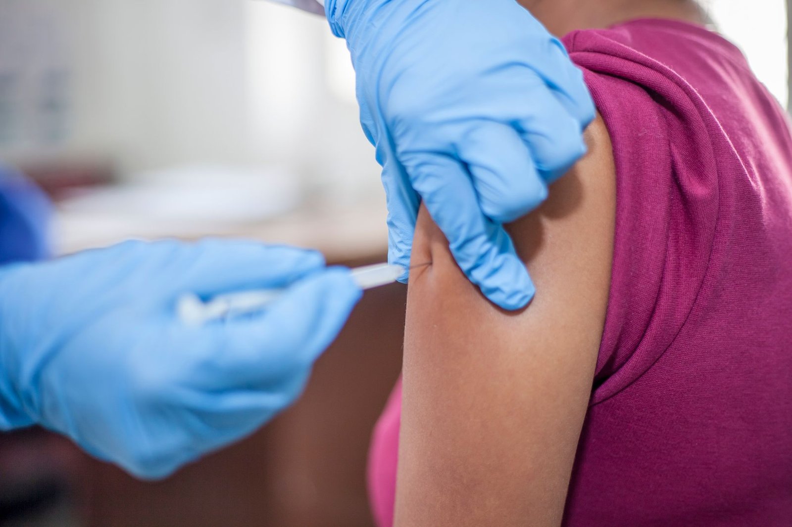 Primer plano de la aplicación de una vacuna en el brazo de un paciente adulto, sin rostros visibles, en un consultorio médico